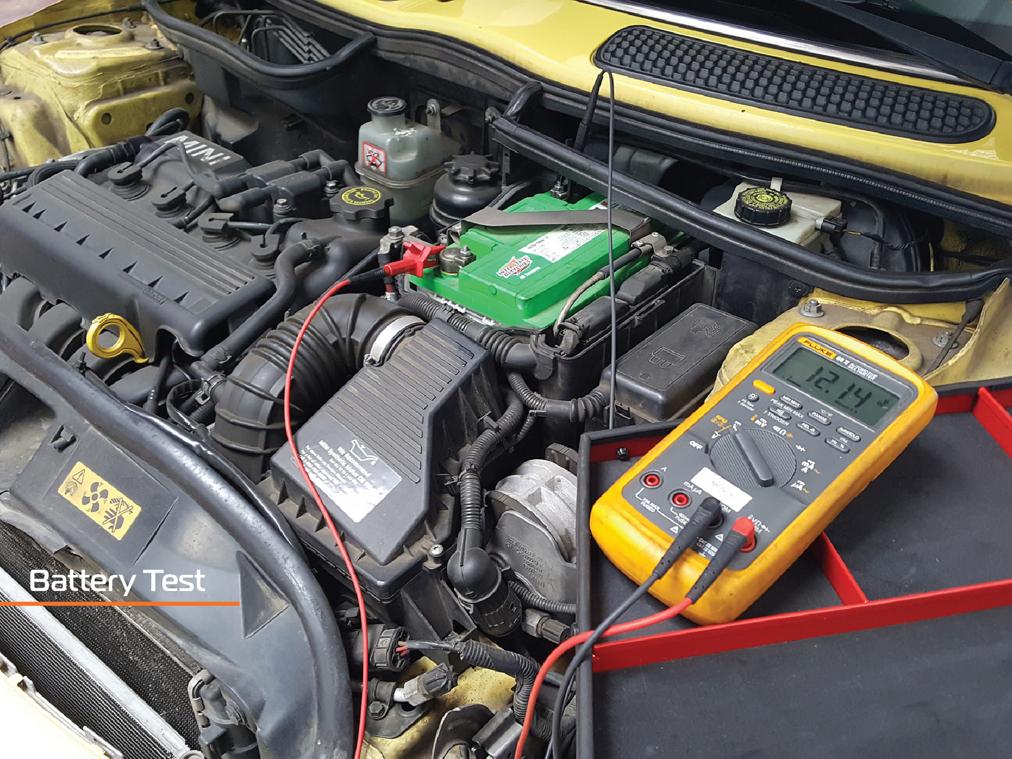 A battery test being done to a yellow mini cooper